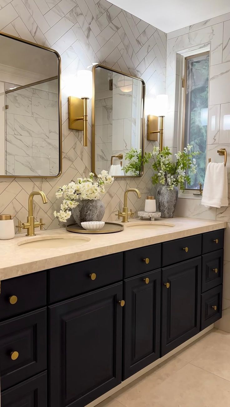 a bathroom with two sinks, mirrors and gold fixtures on the countertop in front of a window