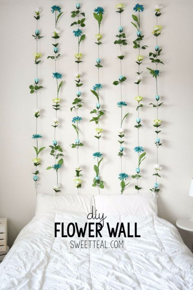 a bed with white sheets and blue flowers hanging from the headboard on it's side