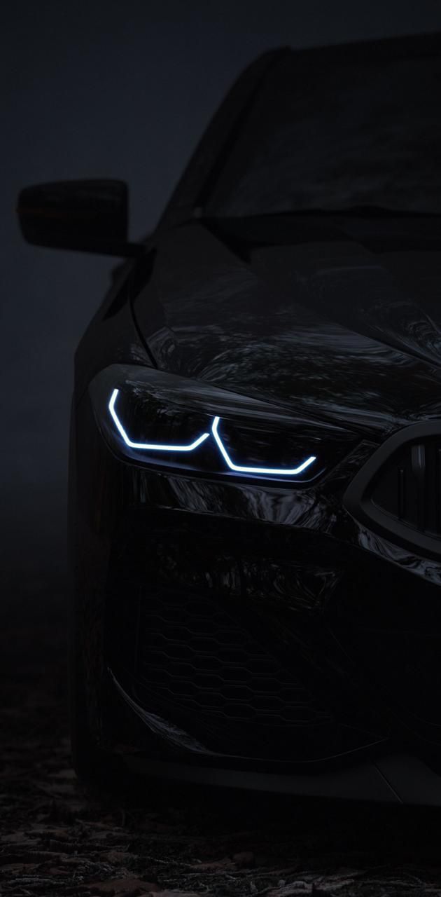 the front end of a black car with its lights on