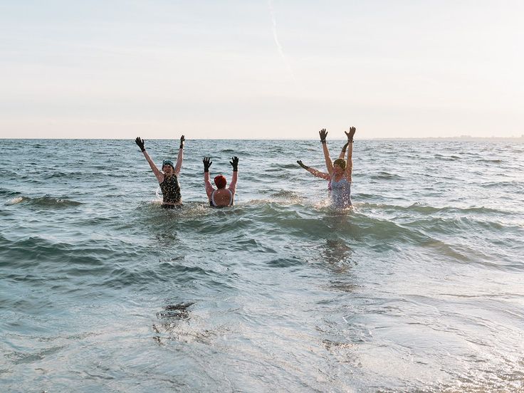 three people in the water holding their hands up