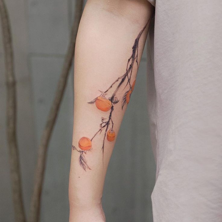 a person with a tattoo on their arm that has oranges growing from the branch