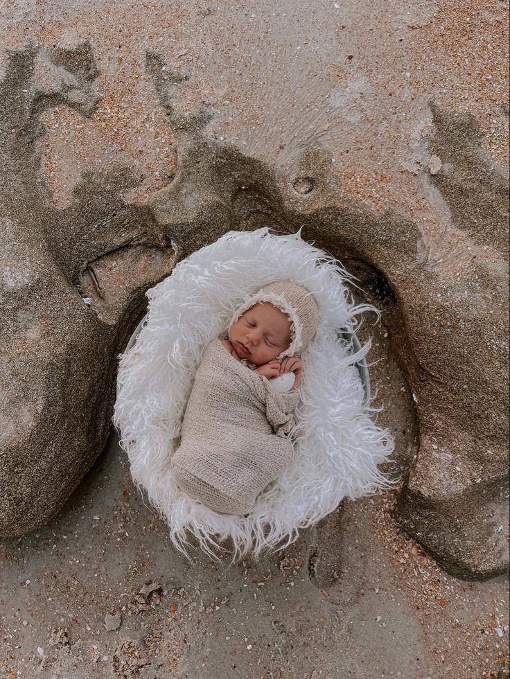 a newborn baby wrapped in a blanket on some rocks