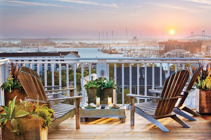 two chairs sitting on top of a wooden deck next to potted plants and candles