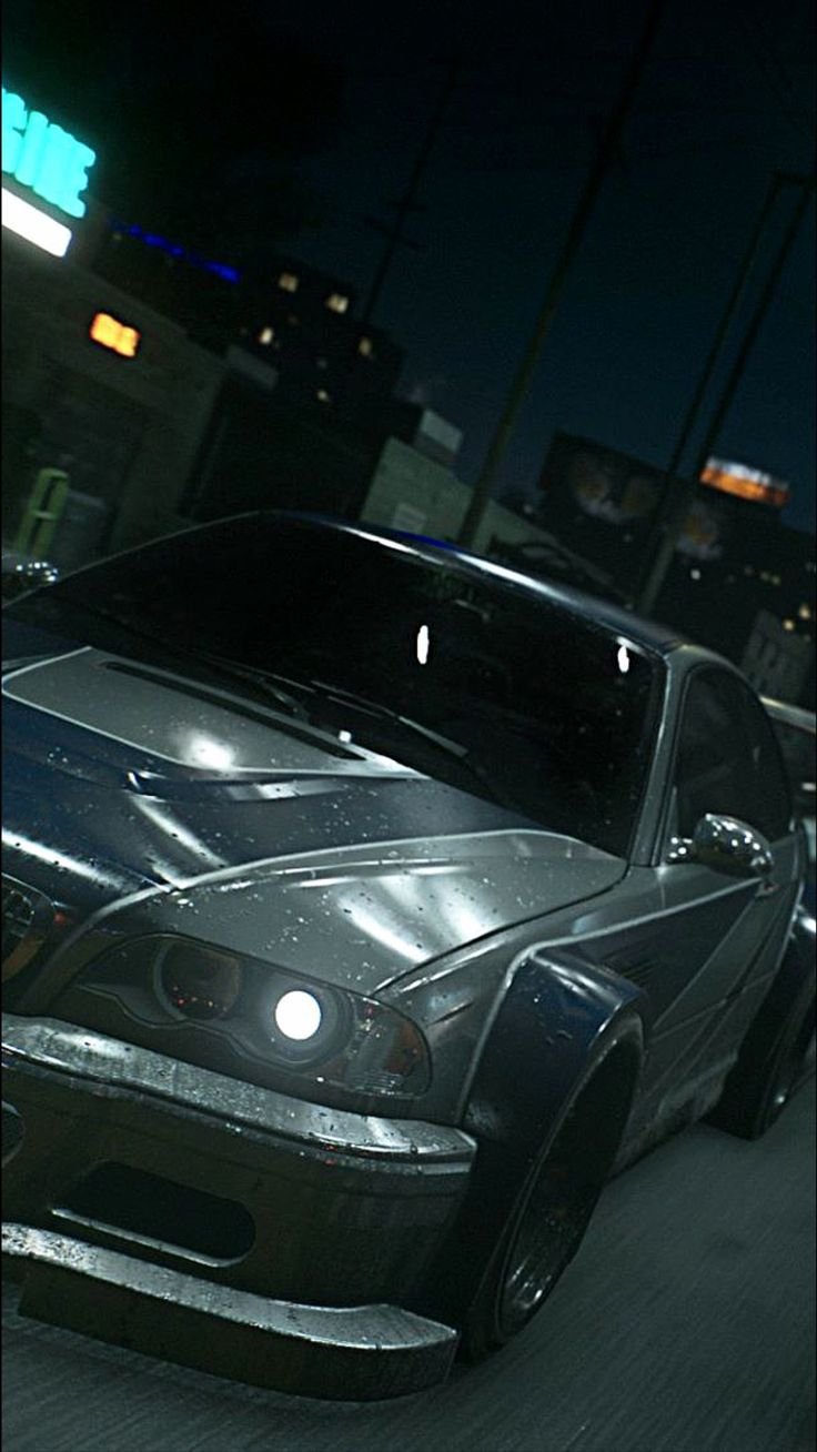 a black car driving down a city street at night with its headlights on and the hood up