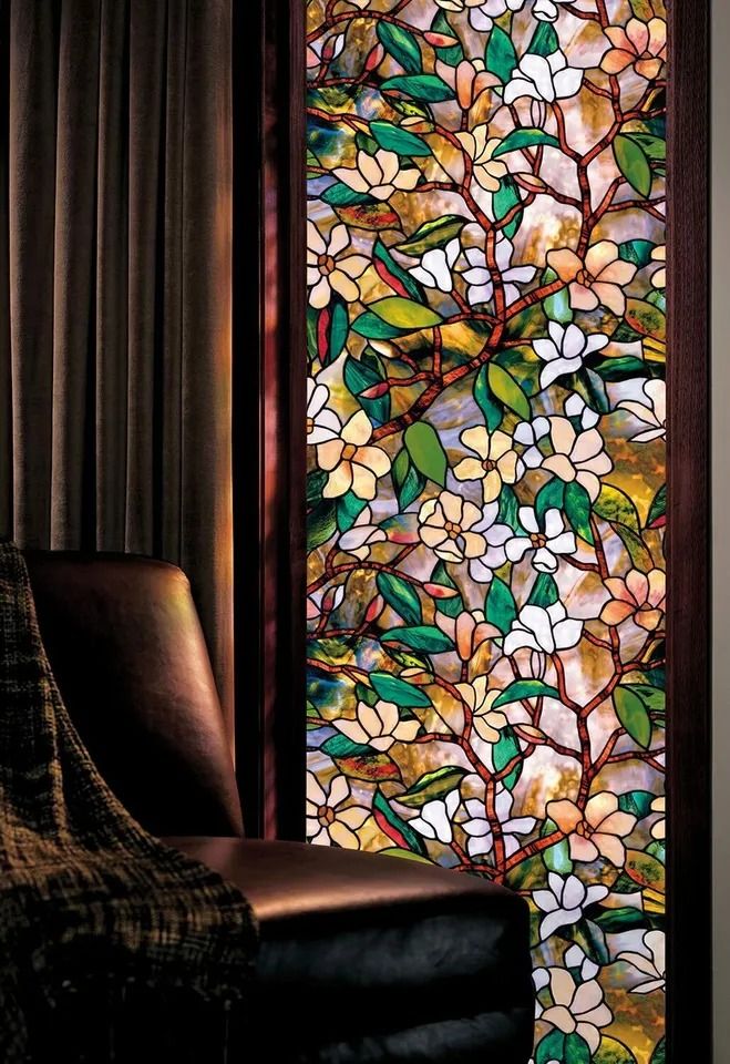 a chair sitting in front of a window covered in stained glass flowers and leaves,