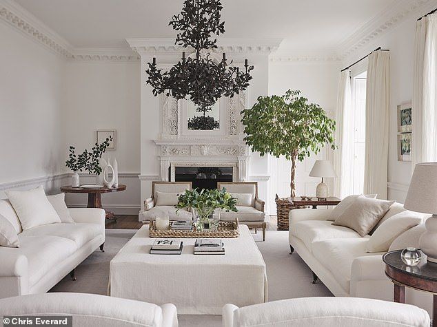 a living room filled with white furniture and a chandelier hanging from the ceiling