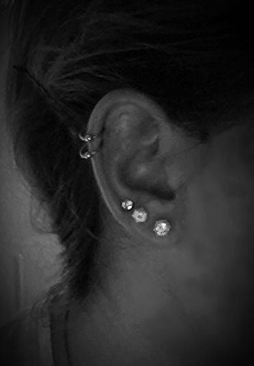 black and white photograph of a woman's ear with two piercings on it