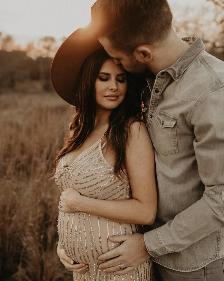 a pregnant woman in a sequin dress standing next to a man wearing a cowboy hat