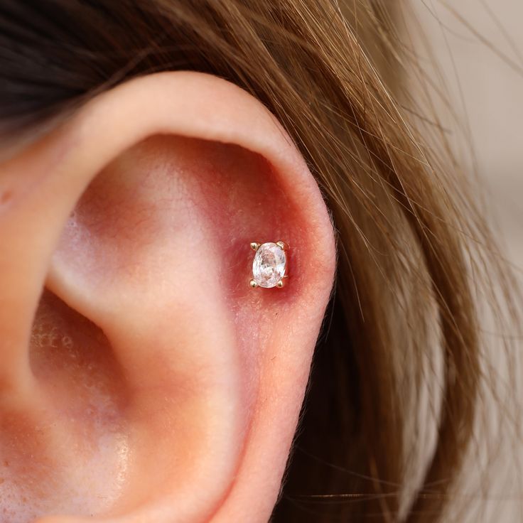 a woman's ear with a single diamond in it