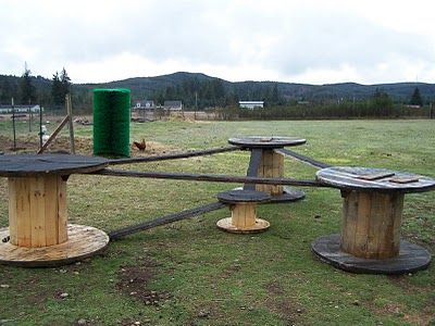 two wooden benches sitting on top of a grass covered field next to a green trash can