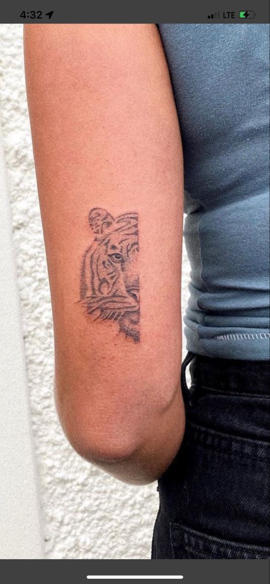 a woman's arm with a tiger tattoo on the left side of her arm