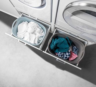 two baskets filled with laundry sitting next to each other on top of a washer and dryer