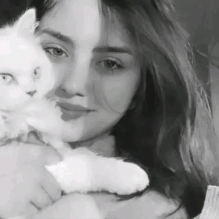 a woman holding a white cat in her arms