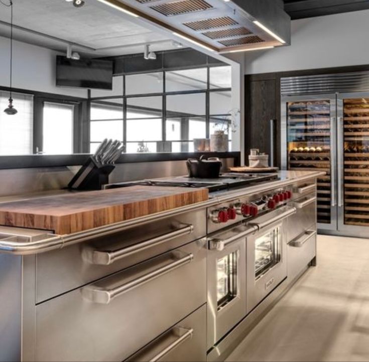 an industrial kitchen with stainless steel appliances and wooden counter tops, along with wine racks