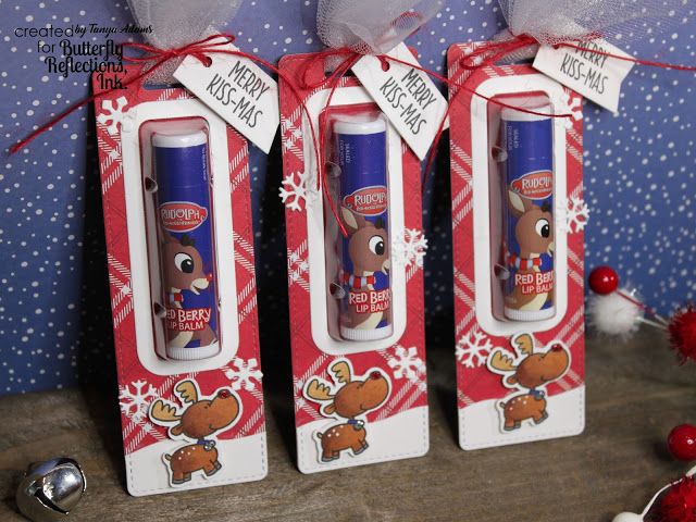 three christmas themed toothpaste tubes in their packaging on a wooden table with red and white snowflakes