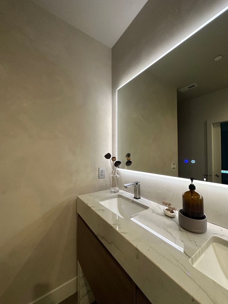 a bathroom sink with a large mirror above it and lights on the wall behind it