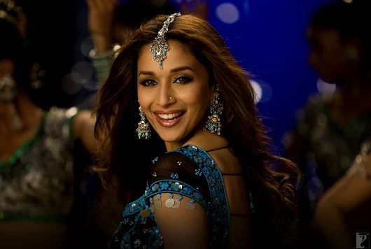 a beautiful woman in a blue dress and headpieces smiles at the camera while posing for a photo