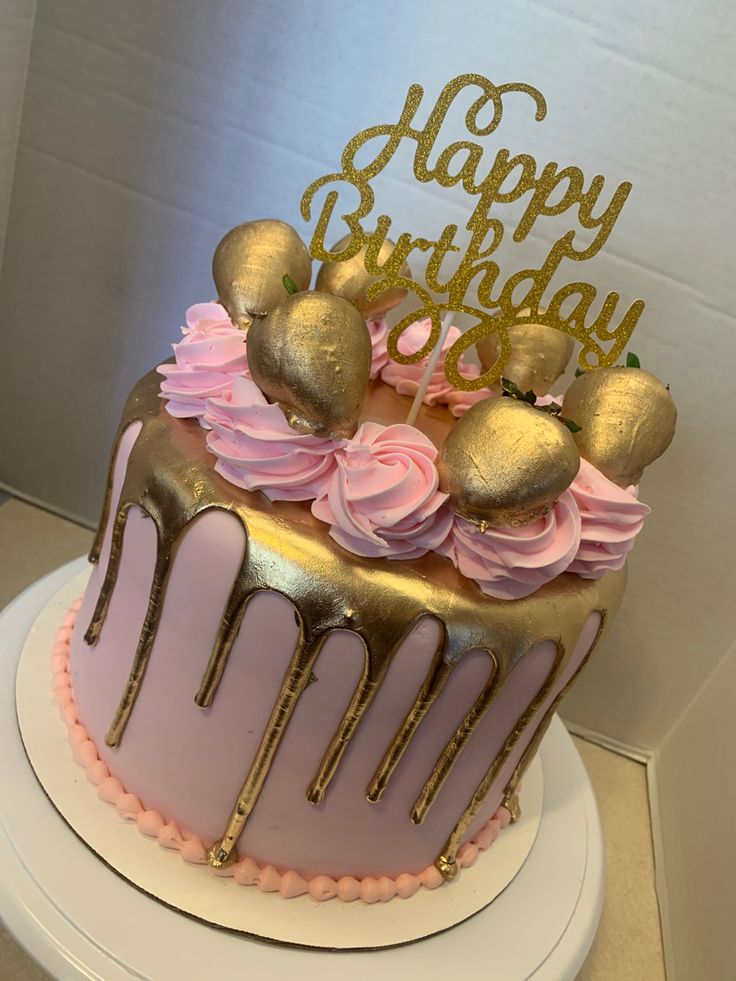 a birthday cake with pink frosting and gold decorations