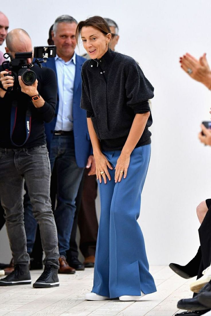 a woman standing in front of a group of people with cameras around her and taking pictures