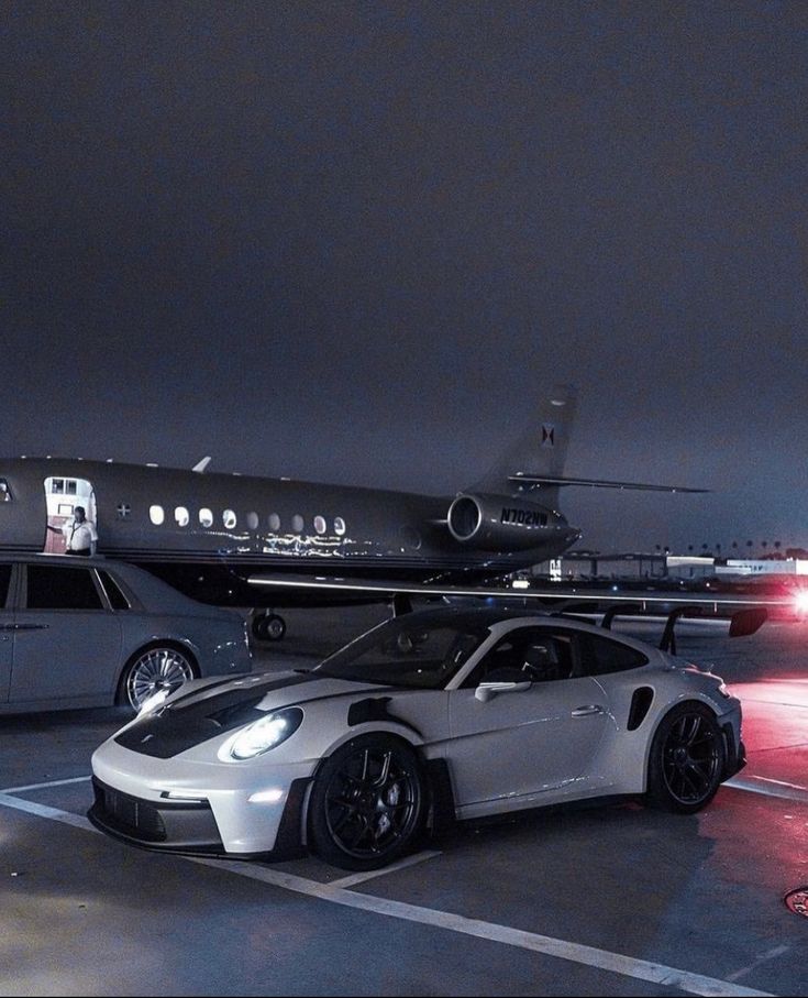 a white sports car parked in front of an airplane