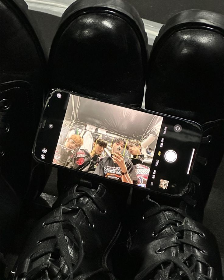 a pair of black shoes sitting on top of each other next to a cell phone