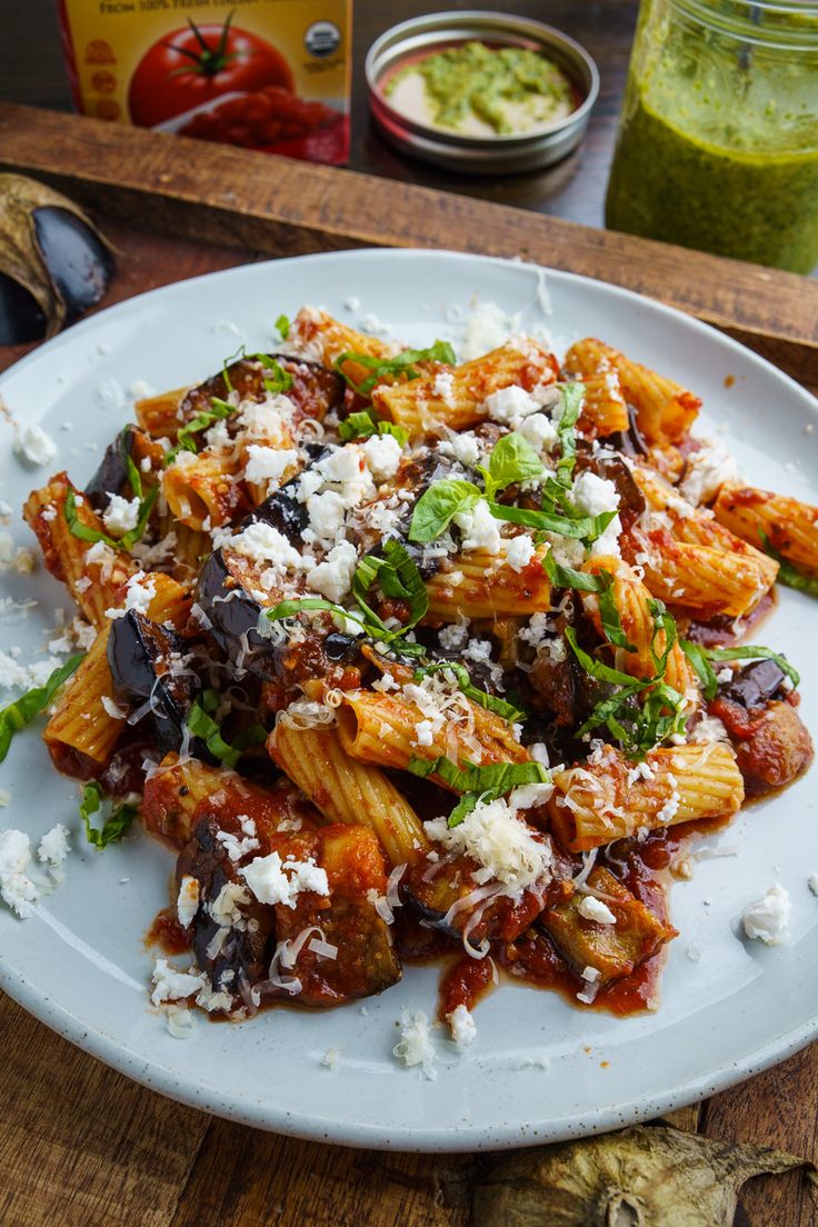 a white plate topped with pasta covered in sauce and parmesan cheese on top of it