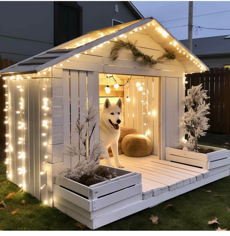 a dog house is decorated with christmas lights and garlands on the roof, along with a planter filled with potted plants