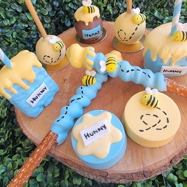 some cupcakes are sitting on top of a tree stump and have bees on them