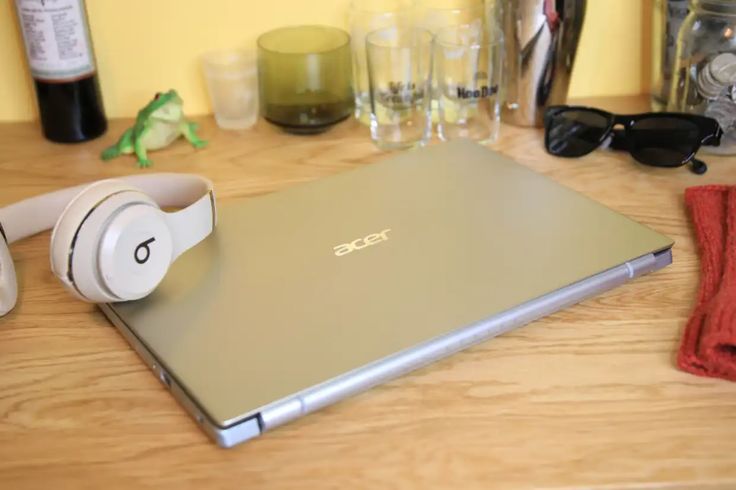 an open laptop computer sitting on top of a wooden table next to headphones and glasses