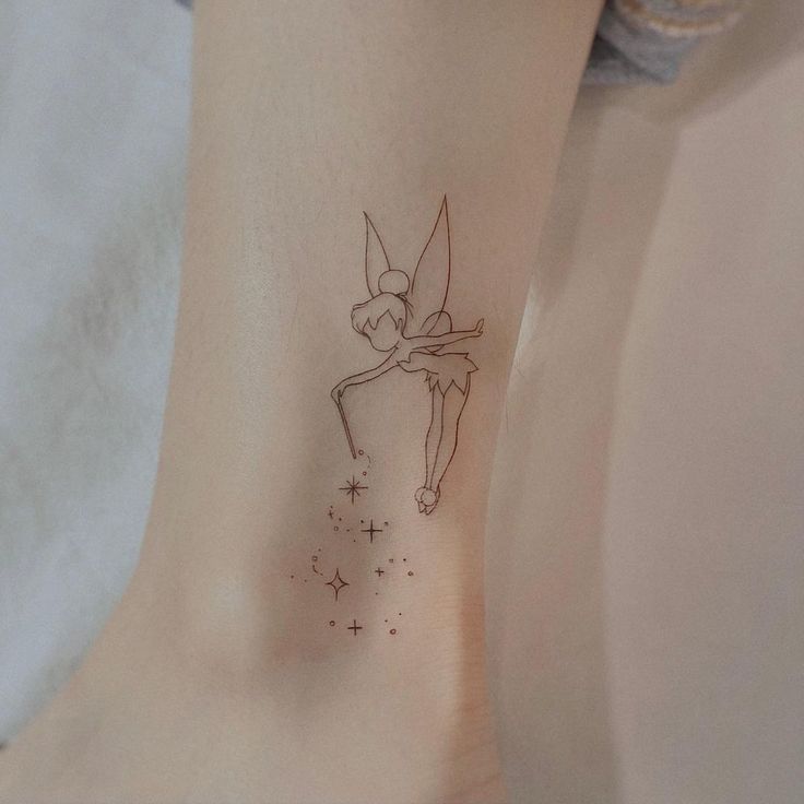 a small tattoo on the ankle of a woman's leg with a fairy tinker