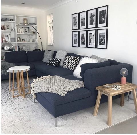 a living room with blue couches and pictures on the wall above them, along with two end tables