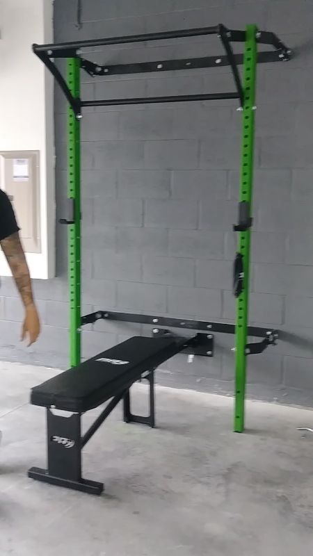 a man standing next to a black bench in a gym with green bars on it