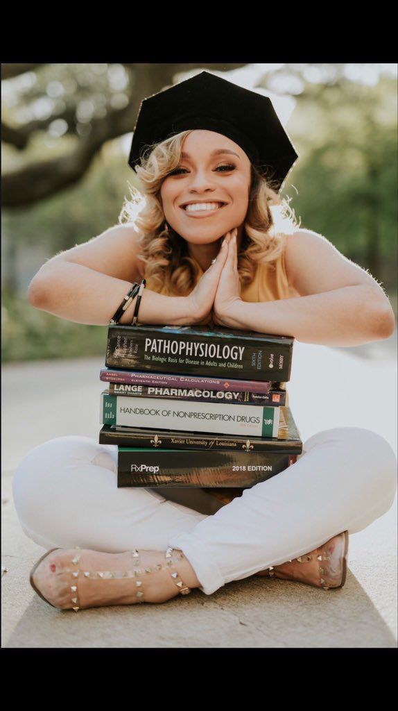 a woman is sitting on the ground with her arms crossed and books stacked in front of her