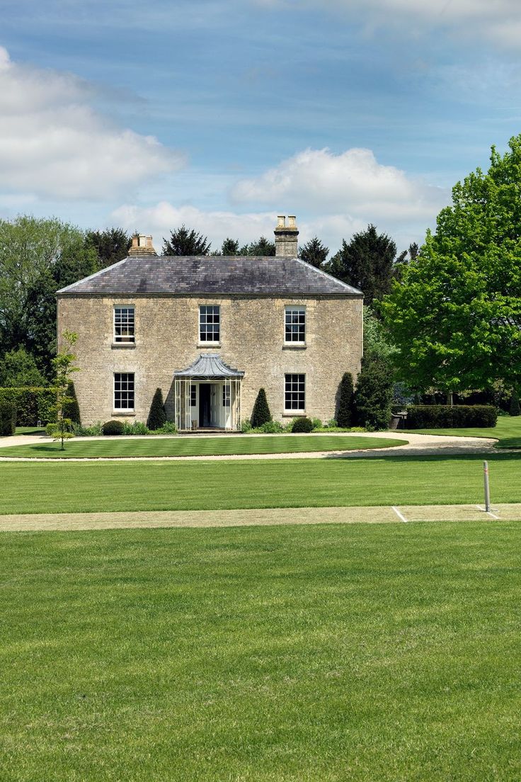 an old brick house with grass and trees around it