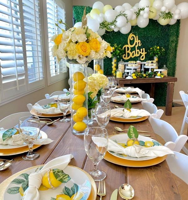 the table is set with plates, silverware and lemons for a baby shower