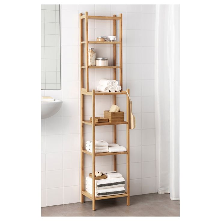 a bathroom shelf with towels, soaps and other items on it in front of a white tiled wall