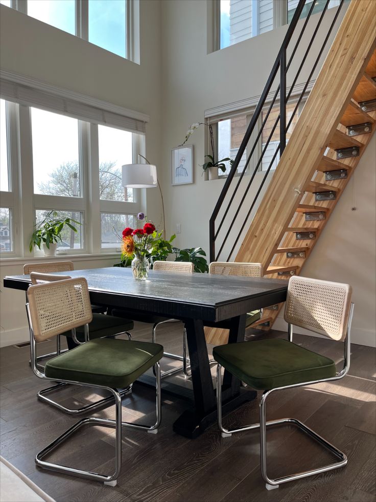 a dining room table with four chairs and a stair case