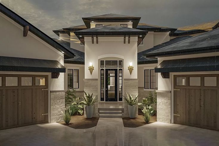 the front entrance to a house with potted plants on either side and lights on