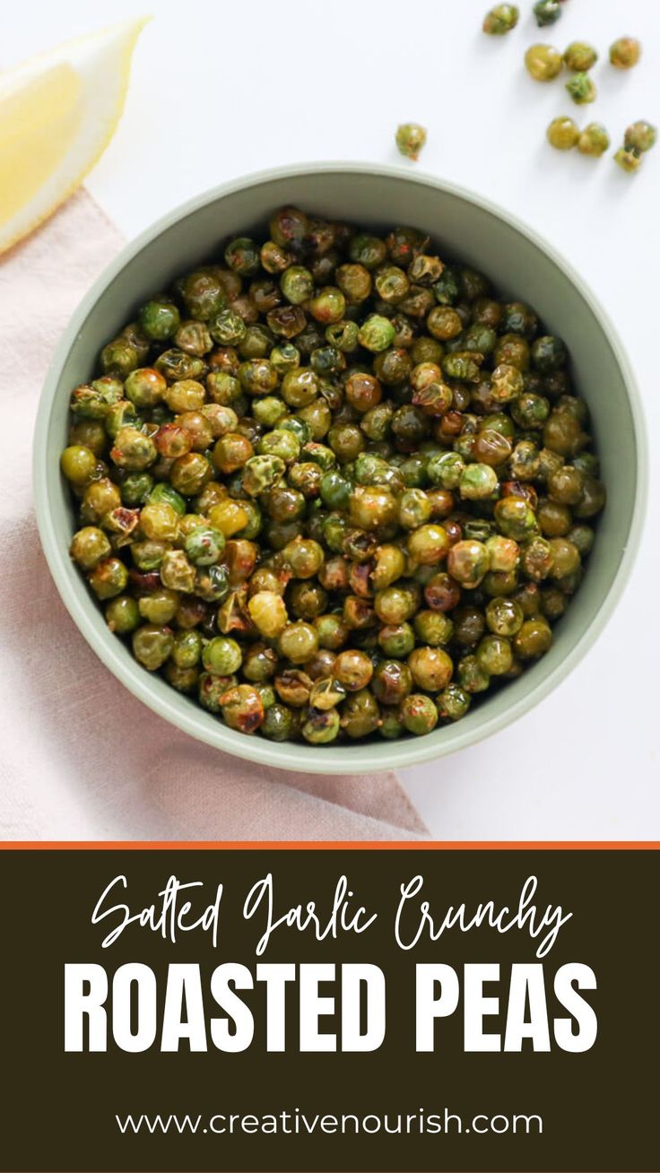 a bowl filled with roasted peas next to a slice of lemon