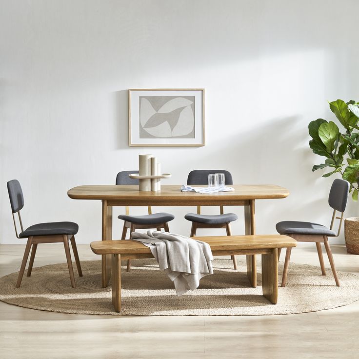 a dining room table with four chairs and a bench in front of it on a rug