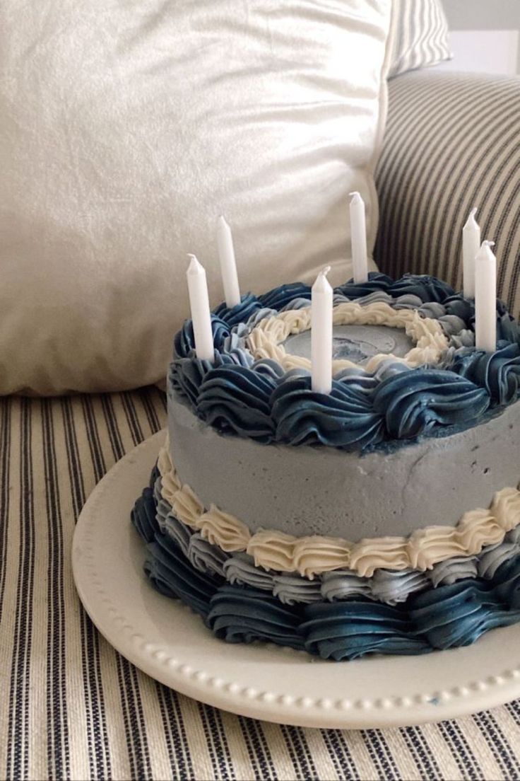 a blue and white cake sitting on top of a table next to a striped pillow