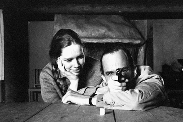 black and white photograph of two people sitting at a table with their arms crossed, looking into the camera