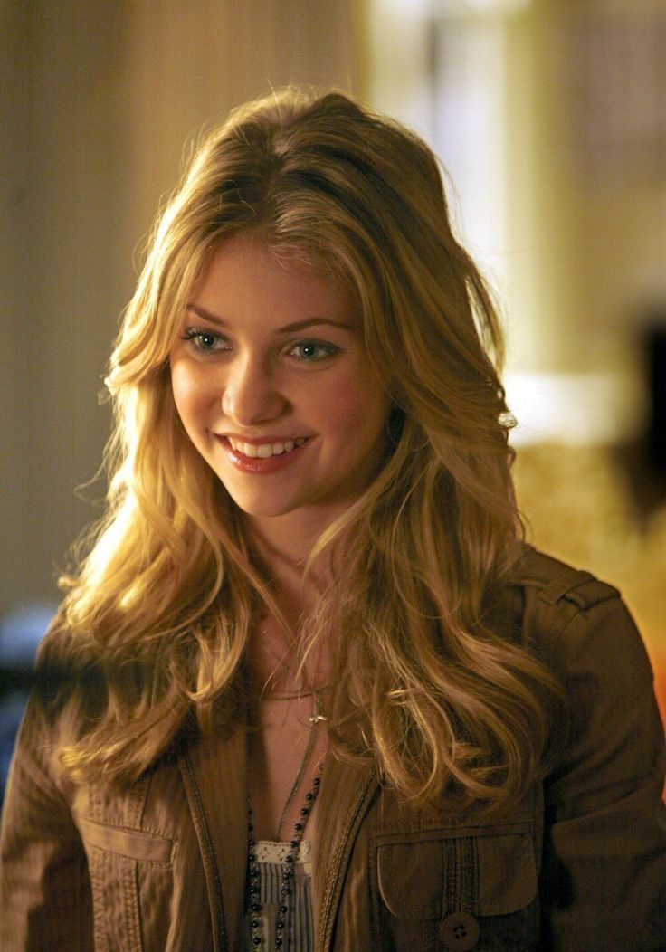 a woman with long blonde hair smiling at the camera