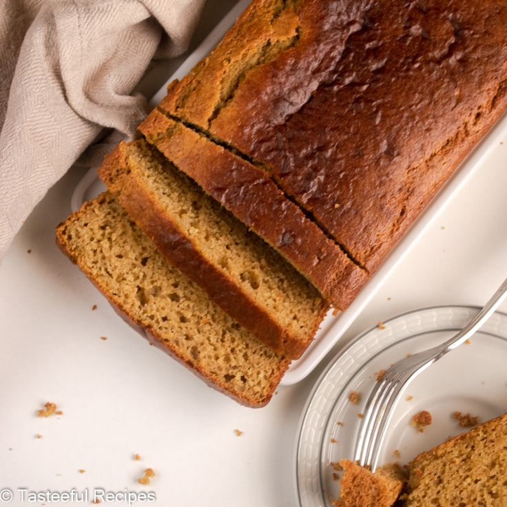 a loaf of banana bread sitting on top of a white plate next to a fork