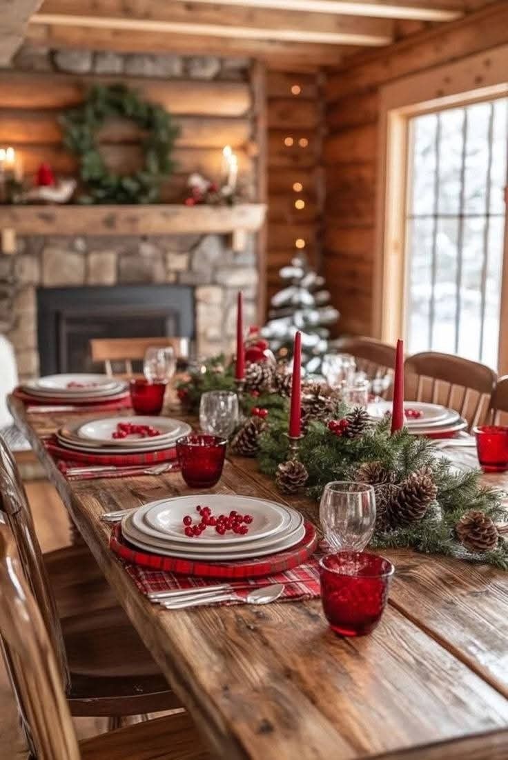 a dining room table set for christmas with red and white place settings, pine cone centerpieces and candles