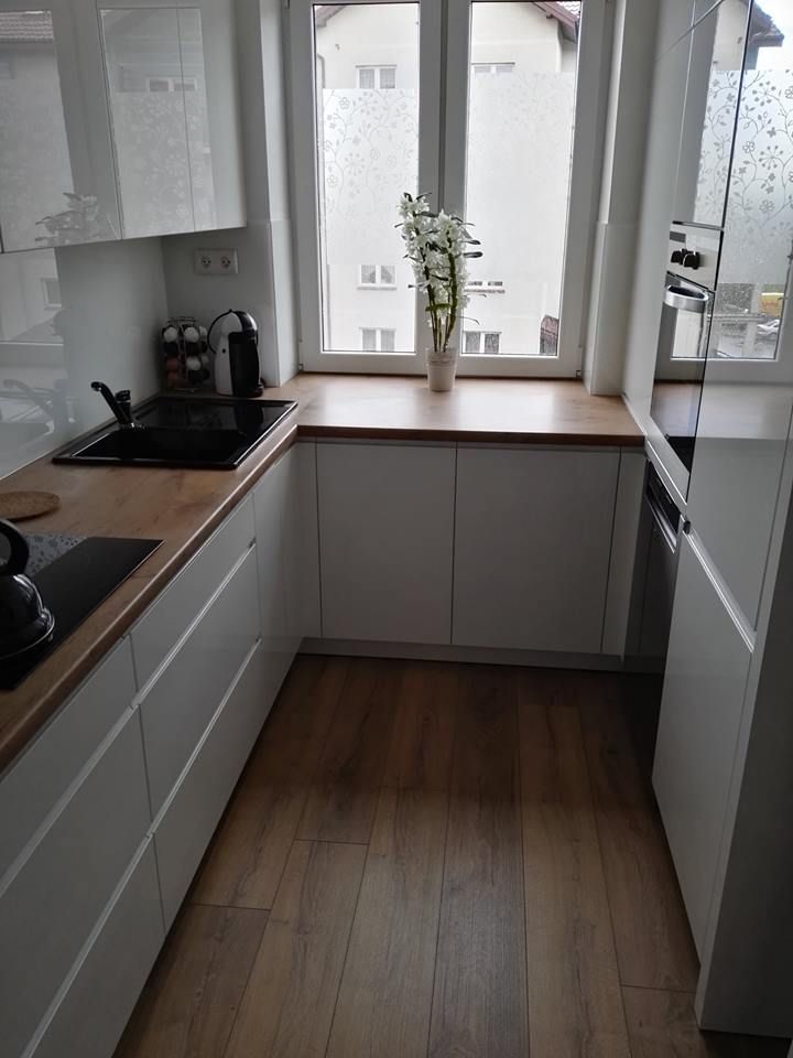 a kitchen with wooden floors and white cabinets, an open window over the stove top