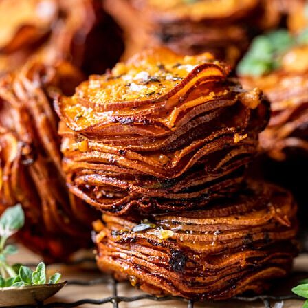 stack of baked sweet potato chips on cooling rack with mint sprig in foreground