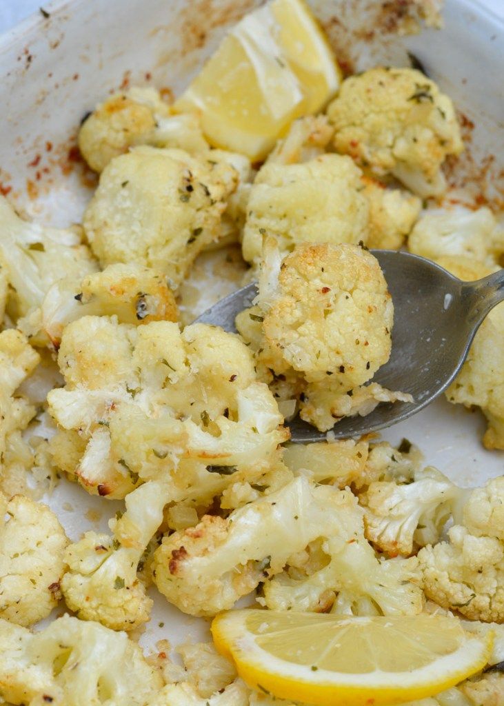 a bowl filled with cauliflower and lemon wedges