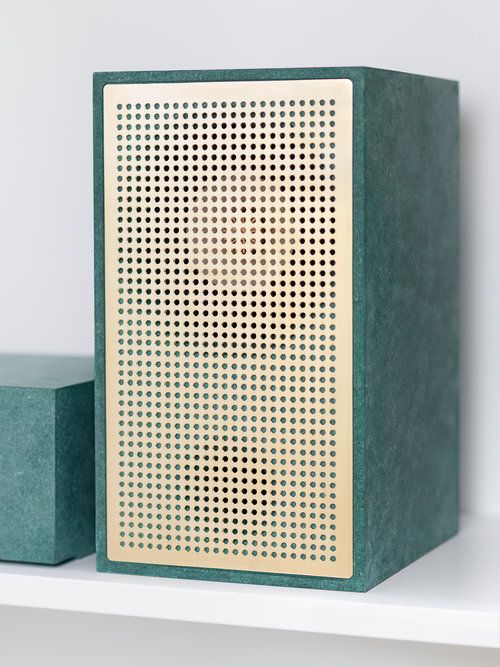 a green box sitting on top of a shelf next to a blue object with holes in it