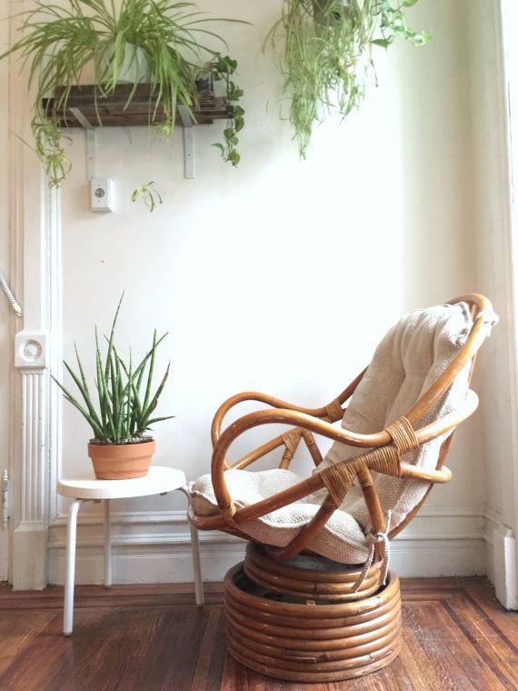 a wicker chair sitting on top of a hard wood floor next to a potted plant